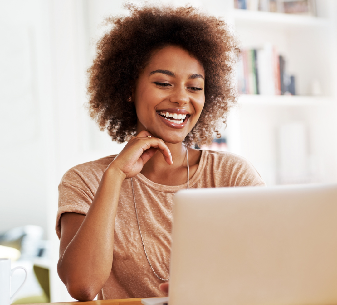 A smiling woman looking at the screen of her laptop