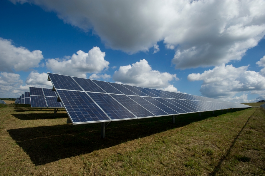 Solar panels in a field with some clouds