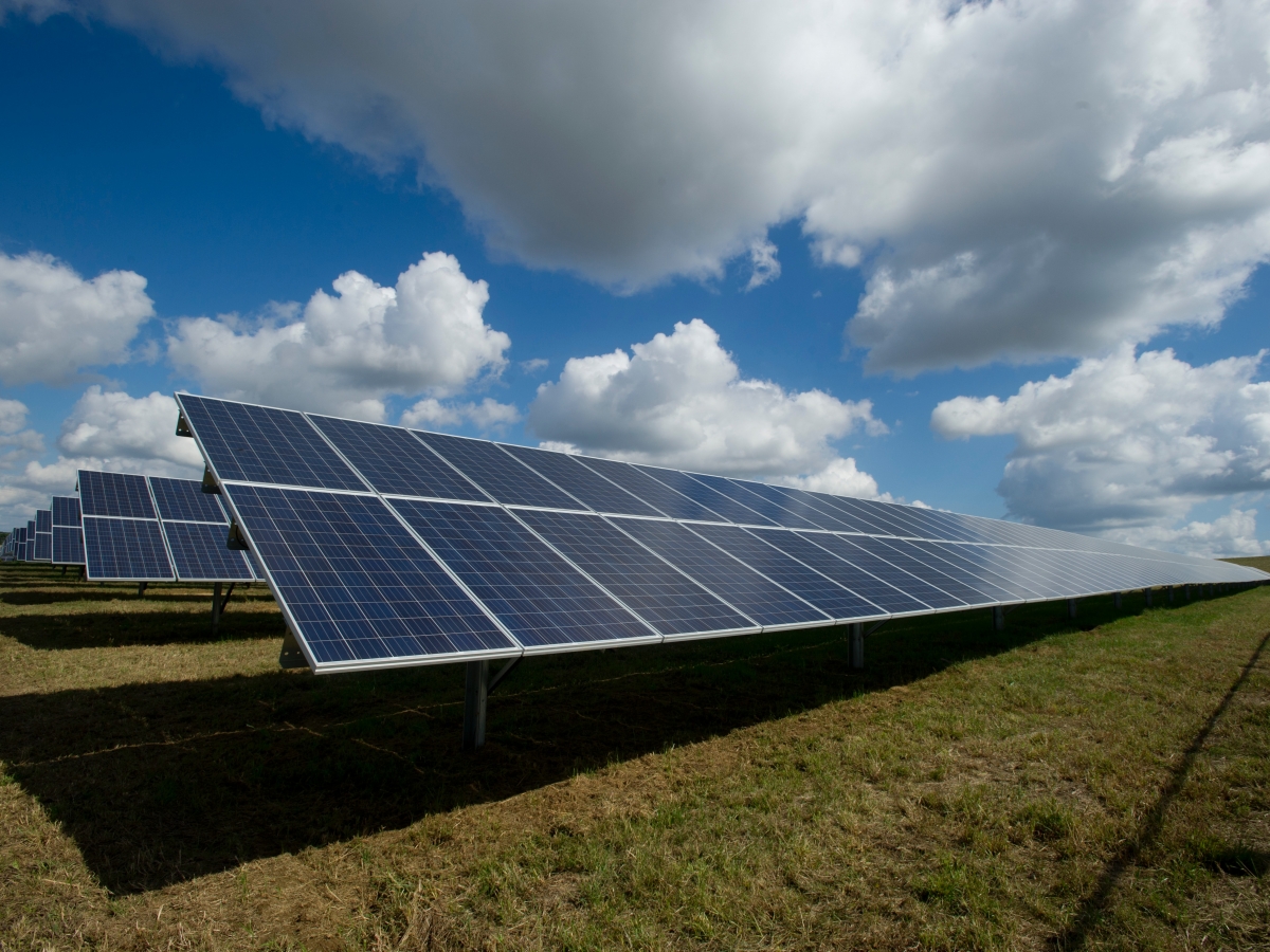 Solar panels in a field with some clouds