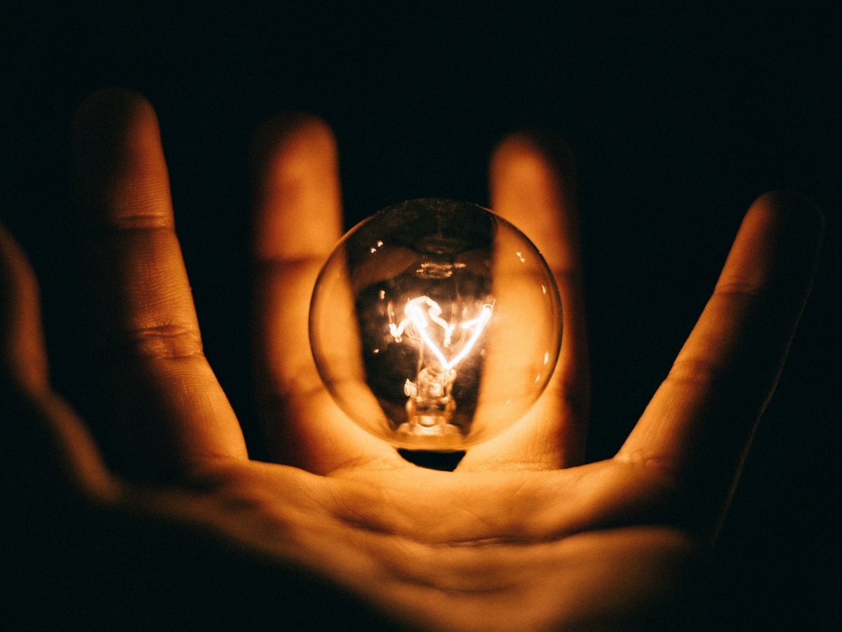 dim light bulb in hand with black background